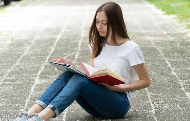 Teenage girl studying sitting on the walkway, outdoors - Foto, imagen