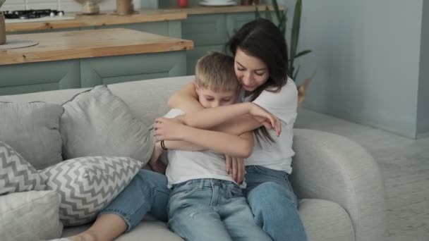 Happy family spending time together in bedtime playing and hugging. Young mother and son having fun on sofa in living room - Video