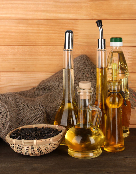 Different types of oil with sunflower seeds on wooden background - Fotografie, Obrázek