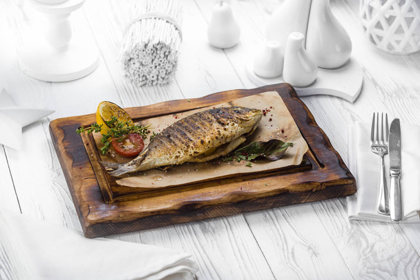 Tasty grilled fish with lemon on a board - 写真・画像