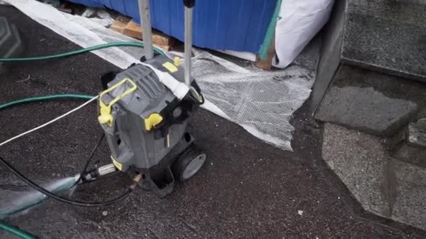 Malá mechanická čerpací jednotka s připojenými hadicemi je umístěna na asfaltové půdě - Záběry, video