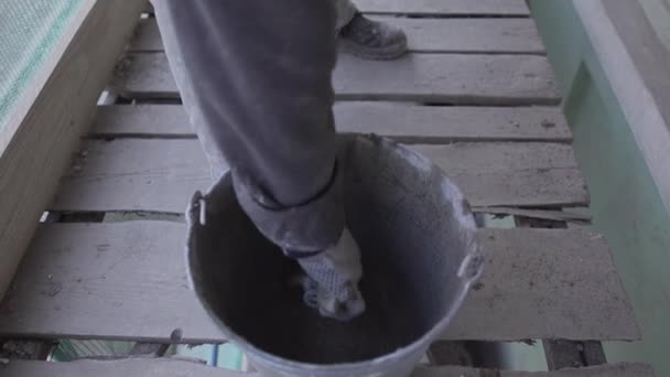 Arbeiterhände entfernen mit Pinsel nasse Betonmasse aus Eimer - Filmmaterial, Video