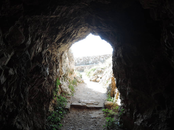 Θέα από το εσωτερικό ενός βραχώδους σπηλαίου στο φρούριο Φορτέλλα, την ελληνική πόλη του Ρεθύμνου. Ο λόφος του Παλαιόκαστρο. Σπήλαιο. - Φωτογραφία, εικόνα