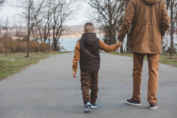 apa fia sétál a parkban kezében kéz - Fotó, kép