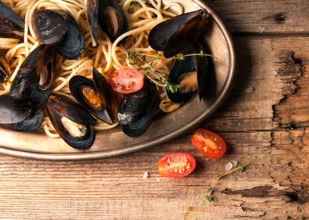 top view of part golden plate with delicious pasta, seafood and sliced cherry tomatoes on wooden textural background - Fotó, kép