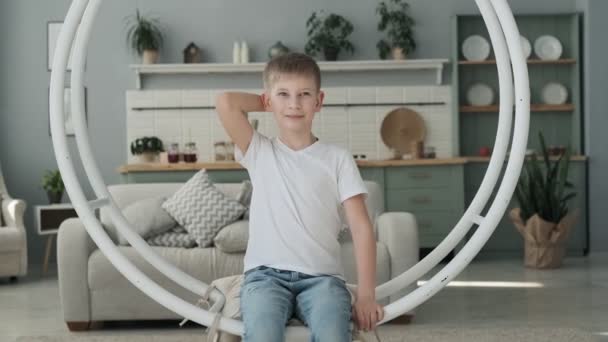 Little boy having fun on swing in living room. Happy son playing in slow motion. - Video, Çekim