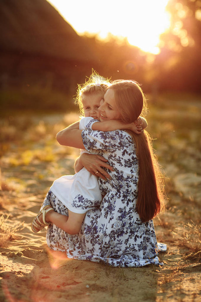 Szczęśliwa rodzina. Koncepcja dnia matki. Matka gra z jej małe dziecko córka dziewczyna na słońcu letni dzień. Piękne światło zachodu słońca w parku. - Zdjęcie, obraz