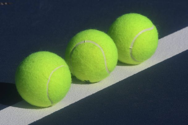 Tennisbälle auf einem Tennisplatz in verschiedenen Designs in abstrakter Form mit kreativer Beleuchtung - Foto, Bild