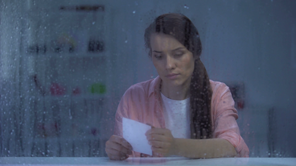Zdenerwowany kobieta patrząc na zdjęcie za oknem deszczowym, brak męża po rozwodzie - Materiał filmowy, wideo