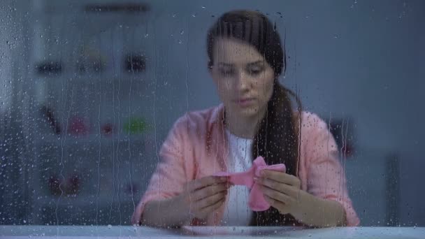 Zdenerwowany kobieta trzyma różowe skarpetki nienarodzonego dziecka w deszczowy dzień, problem niepłodności - Materiał filmowy, wideo