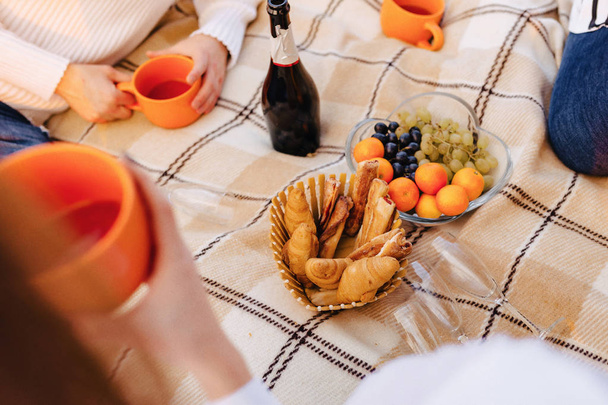 summer picnic on a rug with fruits, wine and tea, cups, croissants and sweets details - Photo, Image