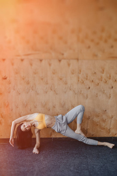 Ahşap bir arka planda yerde Yoga ile Fitness egzersizleri yapan genç çekici kız - Fotoğraf, Görsel