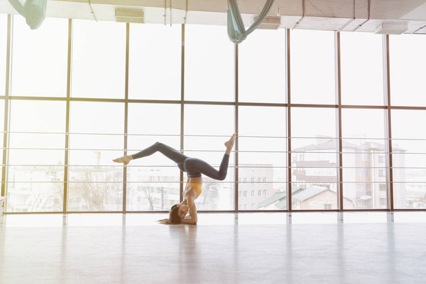 young attractive girl doing fitness exercises with yoga on the floor against the background of panoramic windows - Foto, afbeelding