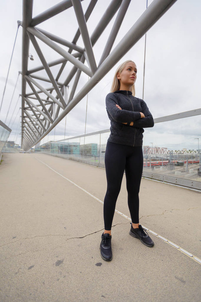 Magabiztos nő fekete edzés Wear állandó a modern Bridge in City - Fotó, kép