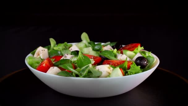 Dieta saludable. La ensalada de la verdura y los trozos del queso los tomates y los pepinos. La placa gira sobre un fondo negro
 - Imágenes, Vídeo
