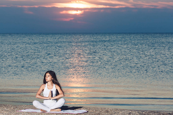 молода дівчина робить йогу на сході сонця на пляжі
. - Фото, зображення