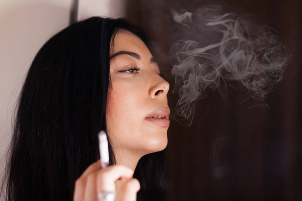 美しい女性がタバコを吸っている - 写真・画像
