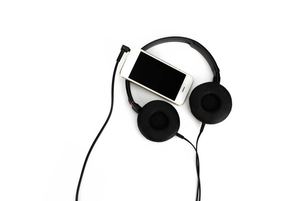 Czarne słuchawki studyjne i inteligentny telefon na białym tle. - Zdjęcie, obraz