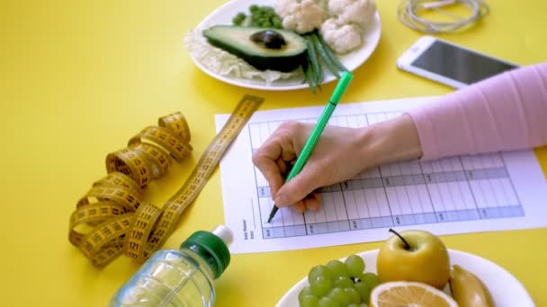 Sağlıklı gıda, diyet, üst görünüm, sarı arka plan kavramı bir fitness takvimi tutmak - Video, Çekim