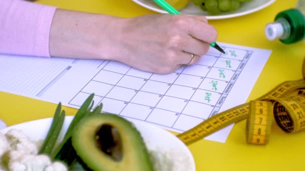Keeping a fitness calendar.concept of healthy food, diet, top view, yellow background - Footage, Video