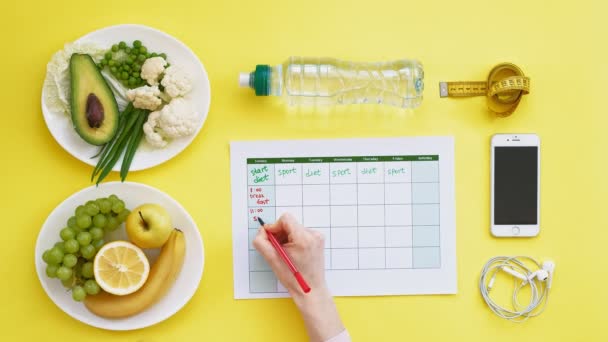 Udržuju fitness kalendář. koncepce zdravých potravin, strava, pohled shora, žluté pozadí - Záběry, video