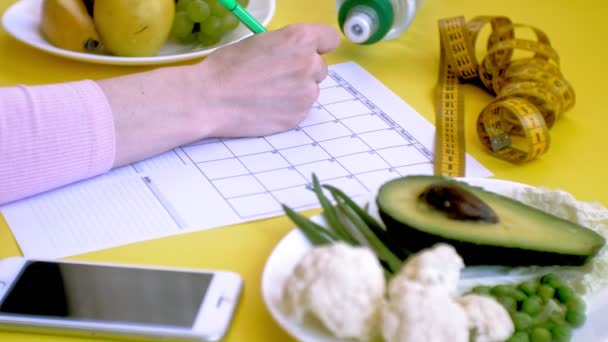 Prowadzenie kalendarza fitness. pojęcie zdrowej żywności, dieta, widok z góry, żółte tło - Materiał filmowy, wideo