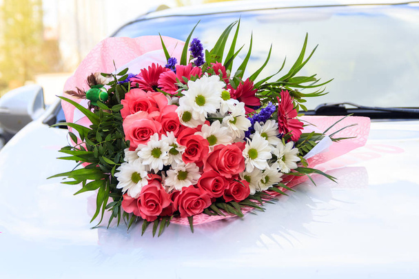 Um buquê de flores está localizado no carro. iluminação natural. flores de rosas e margaridas
. - Foto, Imagem