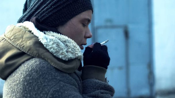 Addicted homeless woman smoking cigarette feeling cold, social problem, poverty - Foto, Imagen