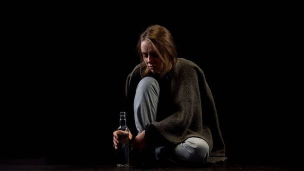 Miserable alcoholic female sitting in darkness with bottle of vodka, addiction - Zdjęcie, obraz