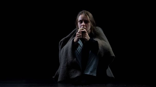 Безнадежная бездомная женщина ест хлеб сидя в темноте, жертва насилия
 - Фото, изображение
