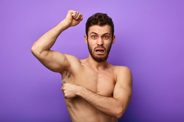Man waxing his armpits to depilate hair - Photo, image