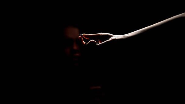 Drug dealer hand offering pill to addicted person in darkness, death substance - 写真・画像