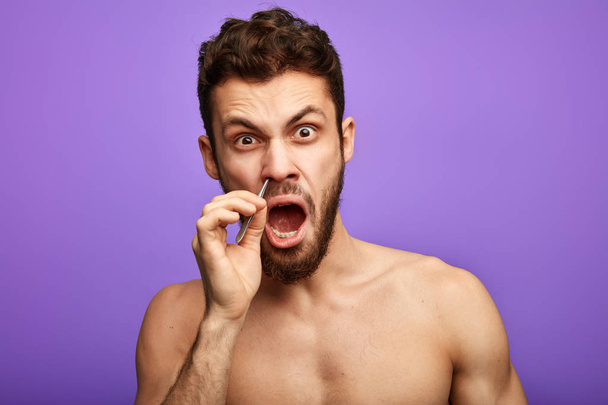 emotional funny man pucking nose hair with tweezers - Valokuva, kuva