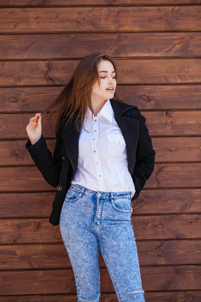 Happy teenager girl in a white shirt on a wooden wall background - Фото, изображение