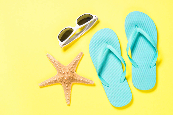 Tongs bleues, lunettes de soleil et étoiles de mer sur fond jaune
. - Photo, image