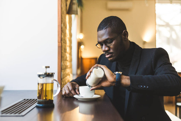 Young handsome dark-skinned businessman in a cafe with a cup of tea. - Fotó, kép