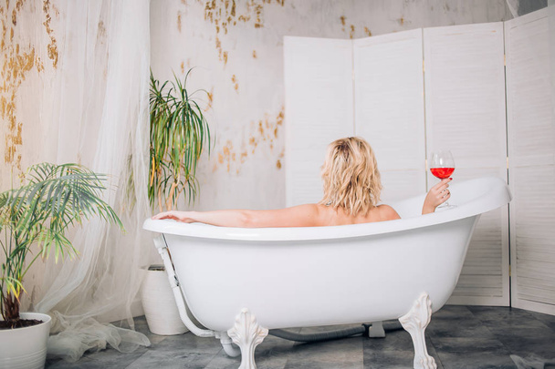 Blonde woman relaxing in bath - 写真・画像