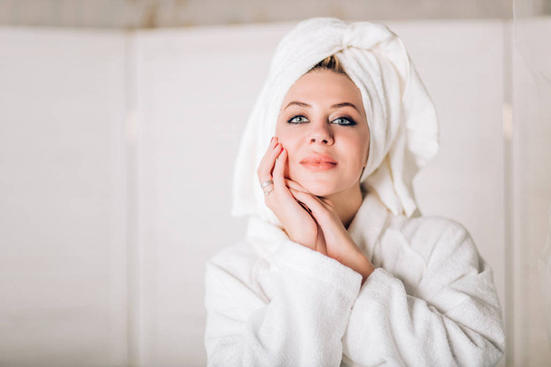 Young smiling woman in bathrobe with towel on head - Foto, imagen