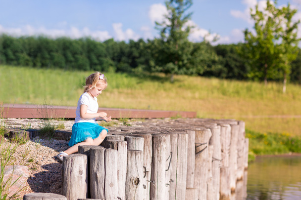 Cute little girl sitting near the lake - Foto, immagini