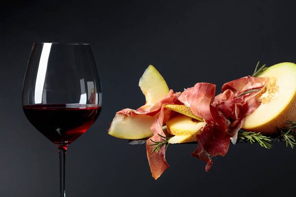 Red wine with prosciutto and melon. - Foto, Bild
