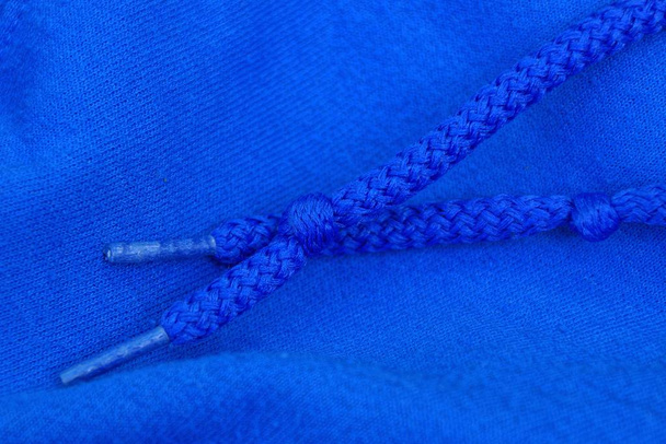 два синих шнурка с узлами на ткани одежды
 - Фото, изображение