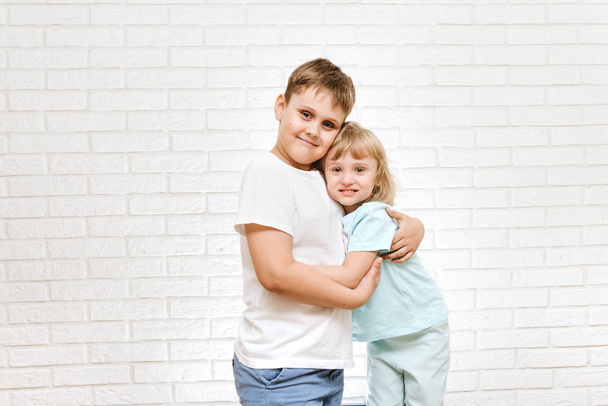 brother and sister hugging against brick sister background - 写真・画像