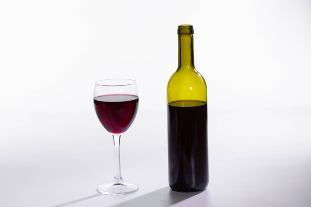 Glas und Flasche mit Rotwein auf weißem Hintergrund - Foto, Bild