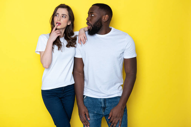 Young interracial couple in white T-shirts posing for camera in studio - Valokuva, kuva