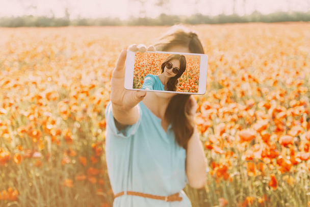 Μελαχρινή γυναίκα λήψη μια φωτογραφία selfie με smartphone σε λουλούδια  - Φωτογραφία, εικόνα