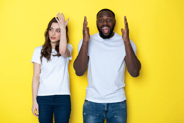 Young interracial couple in white T-shirts posing for camera in studio - Φωτογραφία, εικόνα