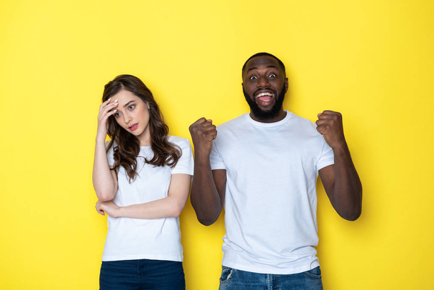 Young interracial couple in white T-shirts posing for camera in studio - Foto, immagini