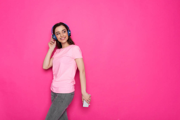 Cropped photo of cheerful brunette Caucasian girl wearing headphones against pink background - Photo, Image