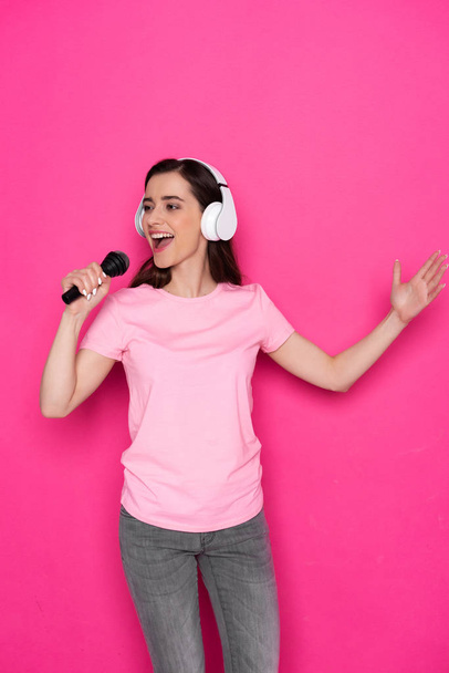 Cropped photo of smiling Caucasian girl wearing headphones and holding microphone - Foto, immagini