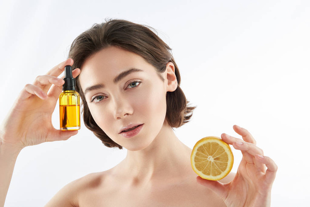 Young naked female with lemon and oil bottle - Фото, изображение